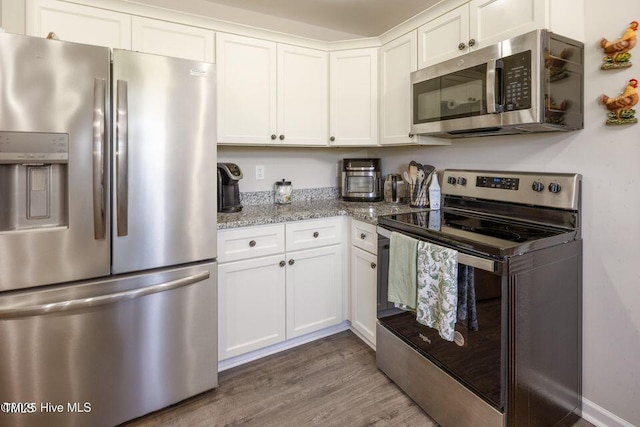 82 Mamie Rd, Benson, NC 27504 - kitchen featuring stainless steel appliances, white cabinets, wood finished floors, and light stone counters