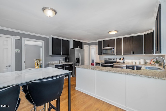 5900 Holly Dr, Raleigh, NC 27616 - kitchen featuring appliances with stainless steel finishes, light stone counters, a peninsula, light wood-style floors, and ornamental molding