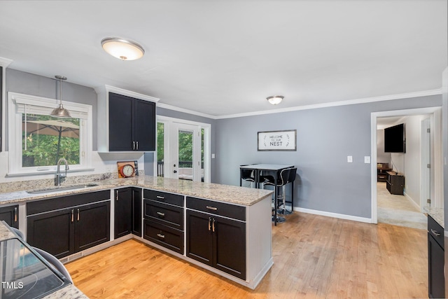 5900 Holly Dr, Raleigh, NC 27616 - kitchen featuring light wood finished floors, a peninsula, light stone countertops, ornamental molding, and hanging light fixtures