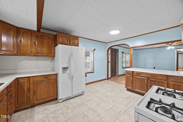7595 Clayton Blvd Unit B, Clayton, NC 27520 - kitchen featuring white appliances, brown cabinetry, arched walkways, light countertops, and light tile patterned flooring