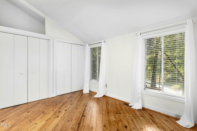 18 Frances St, Chapel Hill, NC 27517 - unfurnished bedroom featuring vaulted ceiling, multiple closets, multiple windows, and light wood-style flooring