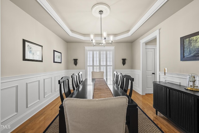 204 Edgepine Dr, Holly Springs, NC 27540 - dining space with a chandelier, a tray ceiling, wainscoting, wood finished floors, and a decorative wall