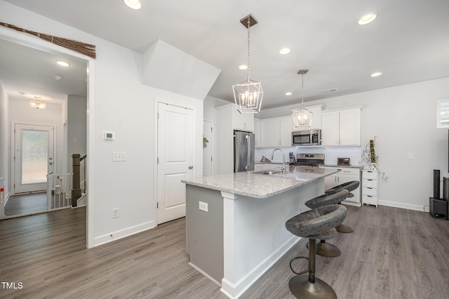 321 Conrad Ln, Wake Forest, NC 27587 - kitchen with appliances with stainless steel finishes, wood finished floors, recessed lighting, white cabinetry, and a kitchen island with sink