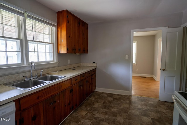 2100 Breeze Rd, Raleigh, NC 27608 - kitchen with range, light countertops, dishwasher, brown cabinetry, and stone finish floors