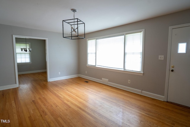 2100 Breeze Rd, Raleigh, NC 27608 - unfurnished dining area with a chandelier, plenty of natural light, and light wood-style floors