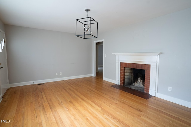 2100 Breeze Rd, Raleigh, NC 27608 - unfurnished living room featuring a chandelier, a fireplace, and light wood-style flooring