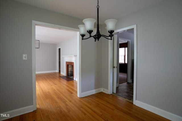 2100 Breeze Rd, Raleigh, NC 27608 - unfurnished dining area with light wood-style flooring, a chandelier, and a fireplace with flush hearth