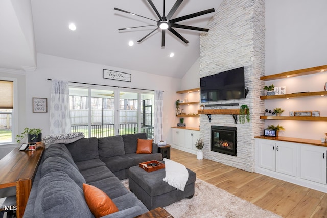 257 Rawhide Dr, Louisburg, NC 27549 - living area featuring high vaulted ceiling, healthy amount of natural light, a stone fireplace, light wood-style floors, and ceiling fan