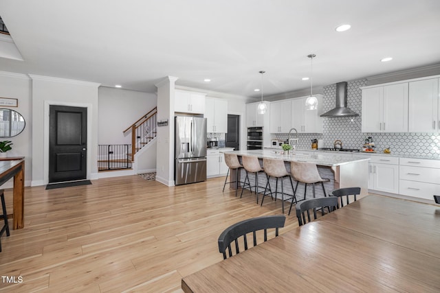 257 Rawhide Dr, Louisburg, NC 27549 - kitchen featuring stainless steel fridge, wall chimney range hood, a kitchen breakfast bar, backsplash, and an island with sink