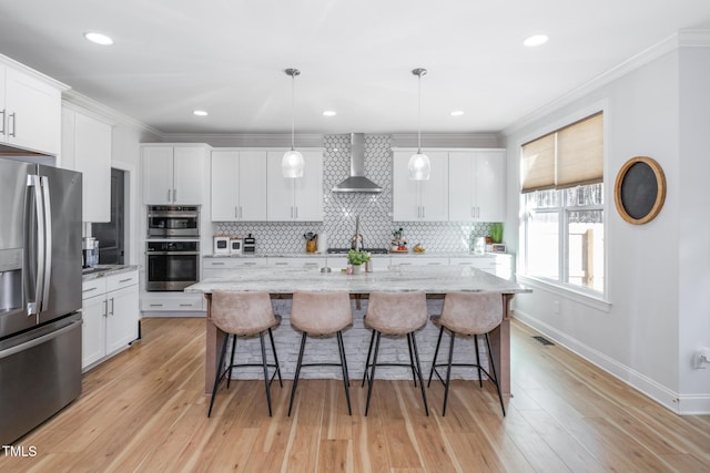 257 Rawhide Dr, Louisburg, NC 27549 - kitchen featuring stainless steel appliances, wall chimney range hood, decorative backsplash, white cabinets, and crown molding