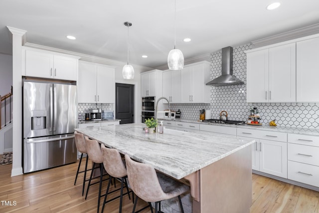 257 Rawhide Dr, Louisburg, NC 27549 - kitchen with appliances with stainless steel finishes, wall chimney range hood, a kitchen island with sink, a kitchen breakfast bar, and white cabinets