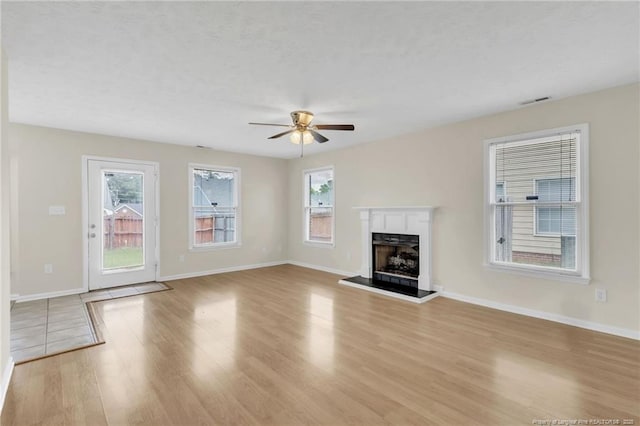 6324 Foxlake Dr, Fayetteville, NC 28314 - unfurnished living room featuring light wood finished floors, ceiling fan, and a fireplace with raised hearth