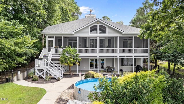 1221 Sagamore Dr, Louisburg, NC 27549 - rear view of house with a sunroom, a shingled roof, a chimney, and a patio