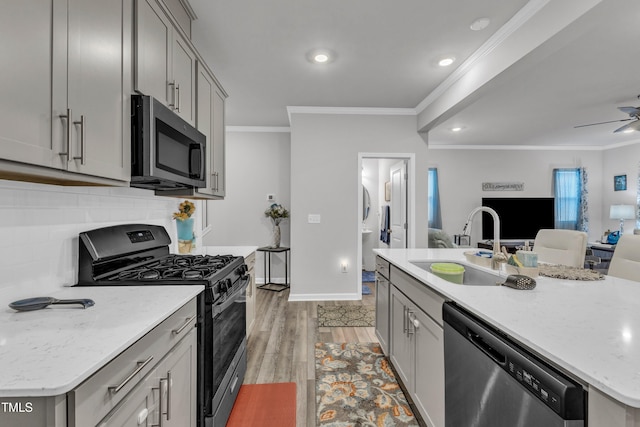 220 Garden Vine Trl, Raleigh, NC 27610 - kitchen featuring appliances with stainless steel finishes, gray cabinetry, open floor plan, crown molding, and light wood finished floors