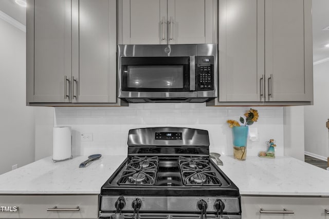 220 Garden Vine Trl, Raleigh, NC 27610 - kitchen featuring stainless steel microwave, gas range, gray cabinets, and crown molding