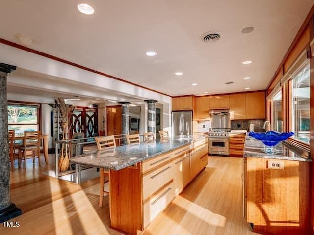 64 Robin Rd, Semora, NC 27343 - kitchen with stainless steel appliances, a kitchen breakfast bar, light wood-type flooring, recessed lighting, and decorative columns