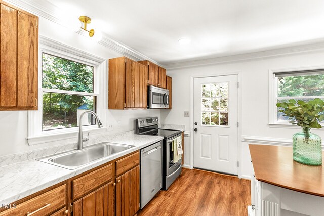 212 Heidinger Dr, Cary, NC 27511 - kitchen with appliances with stainless steel finishes, light countertops, brown cabinets, wood finished floors, and ornamental molding