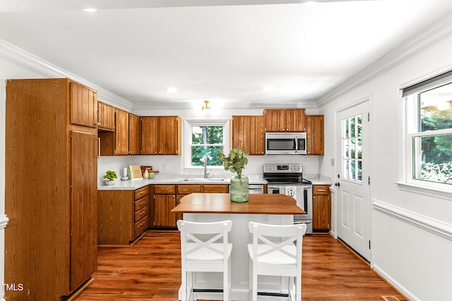 212 Heidinger Dr, Cary, NC 27511 - kitchen with stainless steel appliances, brown cabinets, light countertops, dark wood-style floors, and ornamental molding