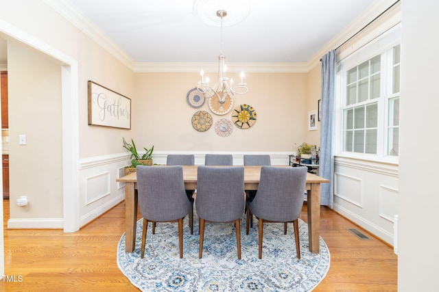 10906 Flower Bed Ct, Raleigh, NC 27614 - dining room featuring a chandelier, crown molding, light wood-style floors, and wainscoting