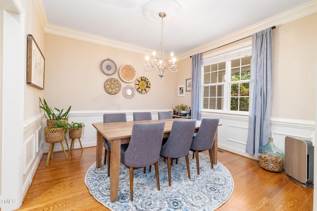 10906 Flower Bed Ct, Raleigh, NC 27614 - dining room featuring a chandelier, ornamental molding, wainscoting, light wood-style flooring, and a decorative wall