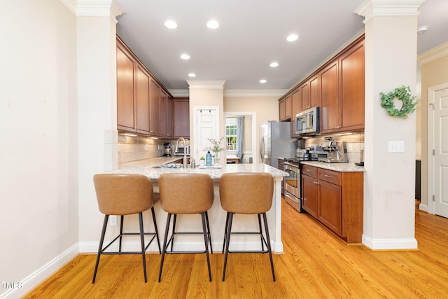 10906 Flower Bed Ct, Raleigh, NC 27614 - kitchen with stainless steel appliances, a peninsula, a kitchen bar, crown molding, and backsplash