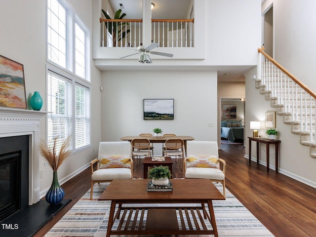 1103 Mallory Ln, Durham, NC 27713 - living area with a high ceiling, a glass covered fireplace, wood finished floors, ceiling fan, and stairs