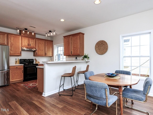 1103 Mallory Ln, Durham, NC 27713 - kitchen with black / electric stove, freestanding refrigerator, under cabinet range hood, brown cabinets, and light countertops