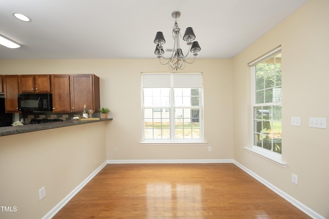 617 Woodson Dr, Clayton, NC 27527 - kitchen with black appliances, a chandelier, brown cabinetry, light wood-style flooring, and pendant lighting