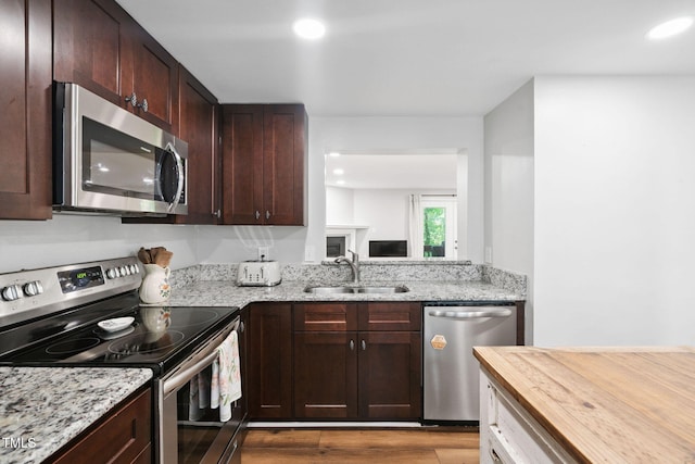 7286 Shellburne Dr, Raleigh, NC 27612 - kitchen featuring stainless steel appliances, wood finished floors, dark brown cabinets, recessed lighting, and light stone countertops