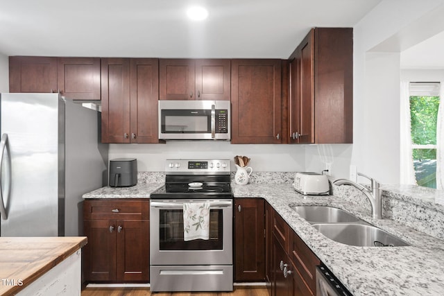 7286 Shellburne Dr, Raleigh, NC 27612 - kitchen with appliances with stainless steel finishes, light stone countertops, light wood-style flooring, and dark brown cabinets