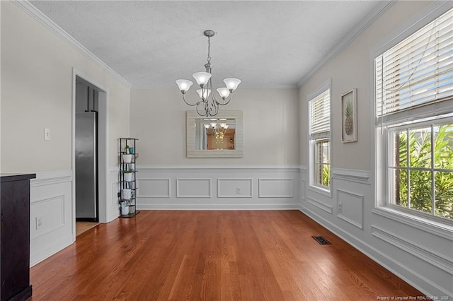 195 Hogart St, Raeford, NC 28376 - unfurnished dining area with a chandelier, wood finished floors, wainscoting, crown molding, and a textured ceiling