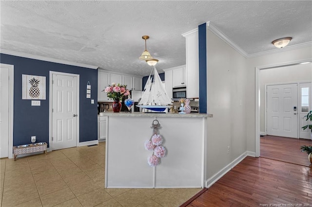 195 Hogart St, Raeford, NC 28376 - kitchen featuring stainless steel microwave, white cabinets, light countertops, a textured ceiling, and ornamental molding