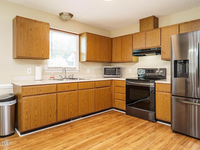 635 Raymond Dr, Wendell, NC 27591 - kitchen with stainless steel appliances, under cabinet range hood, light countertops, light wood-style floors, and a textured ceiling