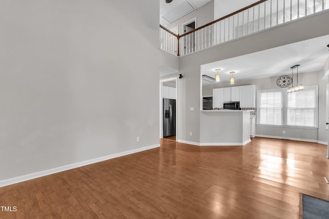 605 Catlin Rd, Cary, NC 27519 - unfurnished living room with wood finished floors, a chandelier, and a towering ceiling