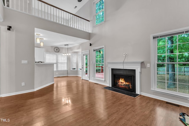 605 Catlin Rd, Cary, NC 27519 - unfurnished living room featuring a lit fireplace, wood finished floors, and a high ceiling