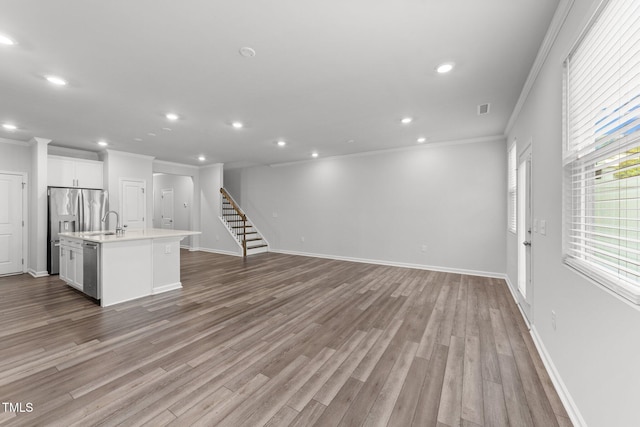 156 Velvet Ridge Way, Garner, NC 27529 - unfurnished living room with ornamental molding, recessed lighting, wood finished floors, and stairway