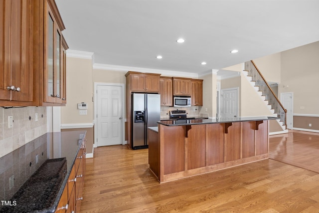 6965 Ogburn Farms Dr, Willow Springs, NC 27592 - kitchen featuring appliances with stainless steel finishes, light wood-type flooring, backsplash, a kitchen bar, and crown molding