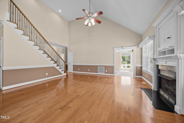 6965 Ogburn Farms Dr, Willow Springs, NC 27592 - unfurnished living room with a ceiling fan, high vaulted ceiling, light wood-style flooring, stairs, and a fireplace