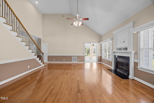 6965 Ogburn Farms Dr, Willow Springs, NC 27592 - unfurnished living room featuring a ceiling fan, light wood-style flooring, a fireplace with flush hearth, high vaulted ceiling, and stairway