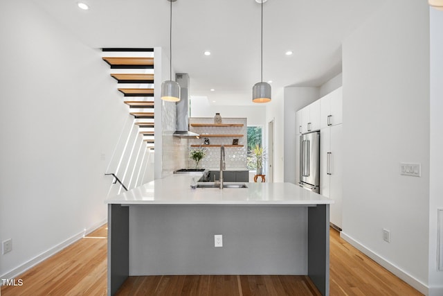 402 Chavis Way, Raleigh, NC 27601 - kitchen with a peninsula, white cabinets, light wood-style flooring, wall chimney exhaust hood, and light countertops