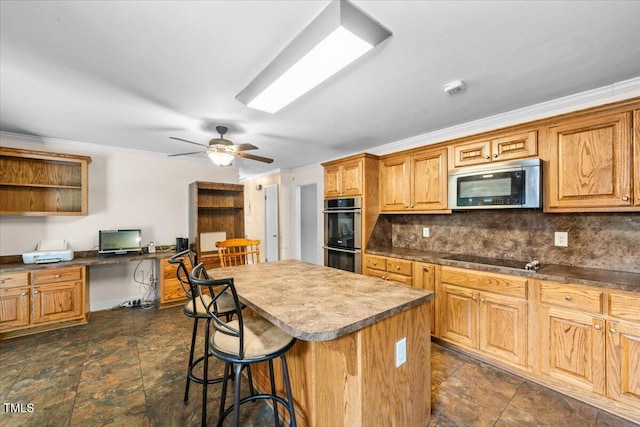 410 W Tenth St, Siler City, NC 27344 - kitchen with appliances with stainless steel finishes, built in study area, a kitchen bar, backsplash, and a kitchen island
