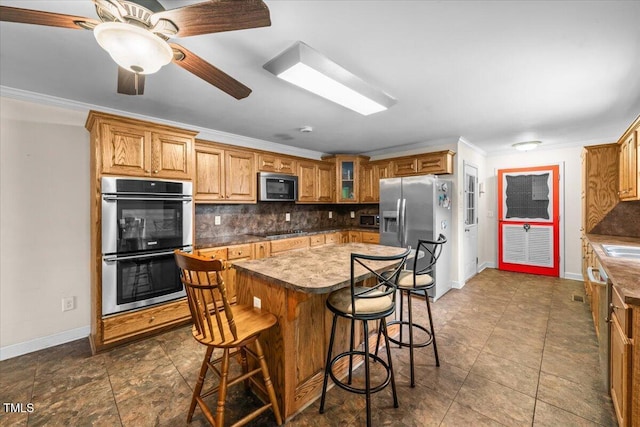 410 W Tenth St, Siler City, NC 27344 - kitchen featuring stainless steel appliances, tasteful backsplash, a breakfast bar area, brown cabinets, and ornamental molding