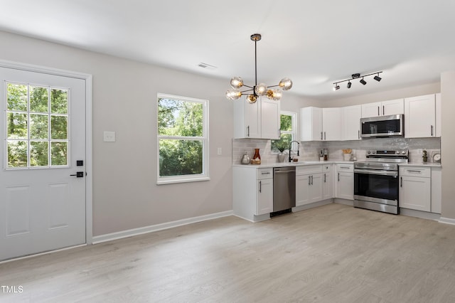 768 Lunar Dr, Raleigh, NC 27610 - kitchen with appliances with stainless steel finishes, light wood-style flooring, tasteful backsplash, and light countertops