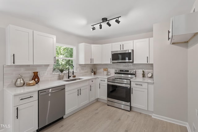 768 Lunar Dr, Raleigh, NC 27610 - kitchen featuring appliances with stainless steel finishes, white cabinets, light wood-type flooring, backsplash, and light countertops