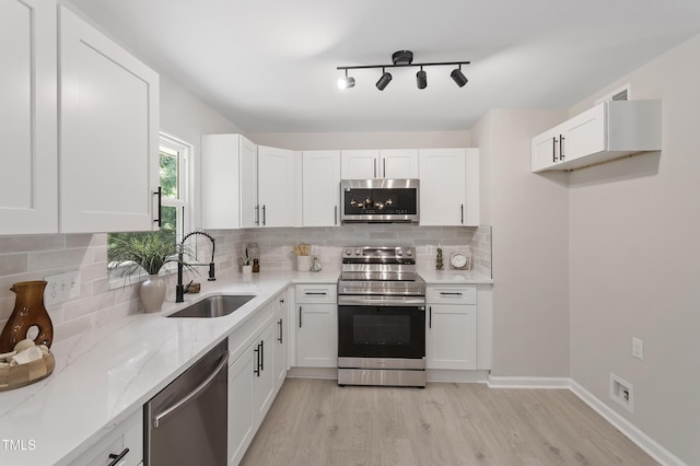 768 Lunar Dr, Raleigh, NC 27610 - kitchen with stainless steel appliances, light stone counters, white cabinetry, and light wood-type flooring