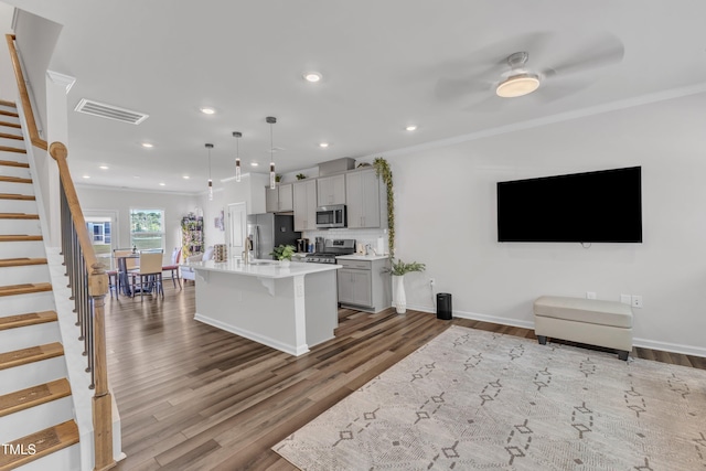 4949 Microcline Trl, Raleigh, NC 27610 - kitchen with stainless steel appliances, crown molding, a breakfast bar area, wood finished floors, and light countertops