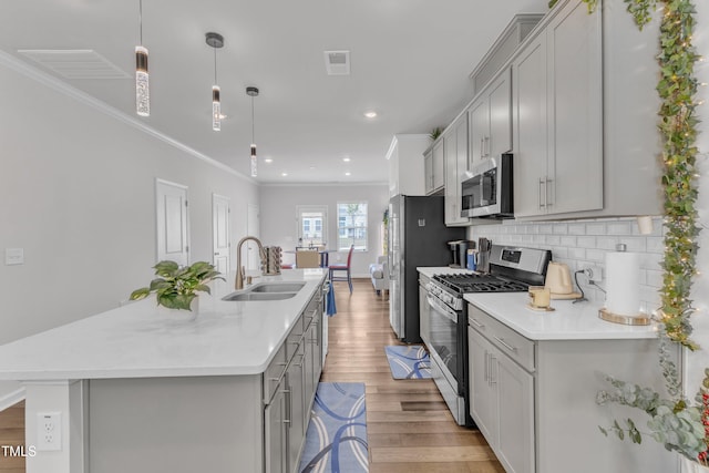 4949 Microcline Trl, Raleigh, NC 27610 - kitchen featuring stainless steel appliances, gray cabinetry, light wood-style floors, light countertops, and crown molding
