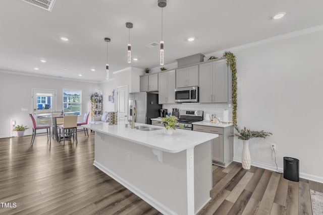 4949 Microcline Trl, Raleigh, NC 27610 - kitchen with stainless steel appliances, decorative backsplash, light countertops, an island with sink, and crown molding