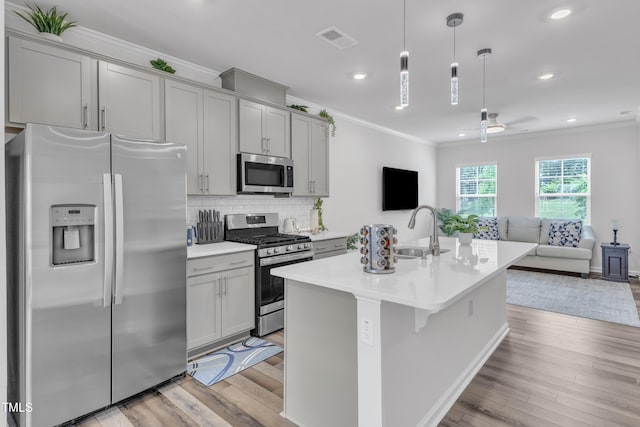 4949 Microcline Trl, Raleigh, NC 27610 - kitchen featuring appliances with stainless steel finishes, gray cabinets, ornamental molding, open floor plan, and light wood-style floors