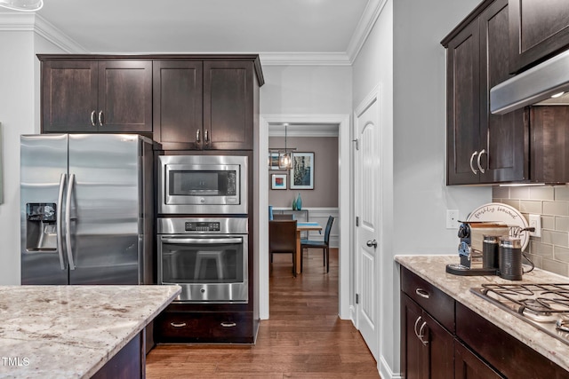 2716 Lake Waccamaw Trl, Apex, NC 27502 - kitchen with stainless steel appliances, crown molding, dark brown cabinetry, under cabinet range hood, and light stone counters